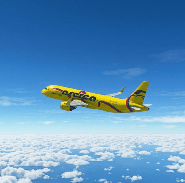 A yellow passenger airplane flying above fluffy white clouds with a clear blue sky in the background.
